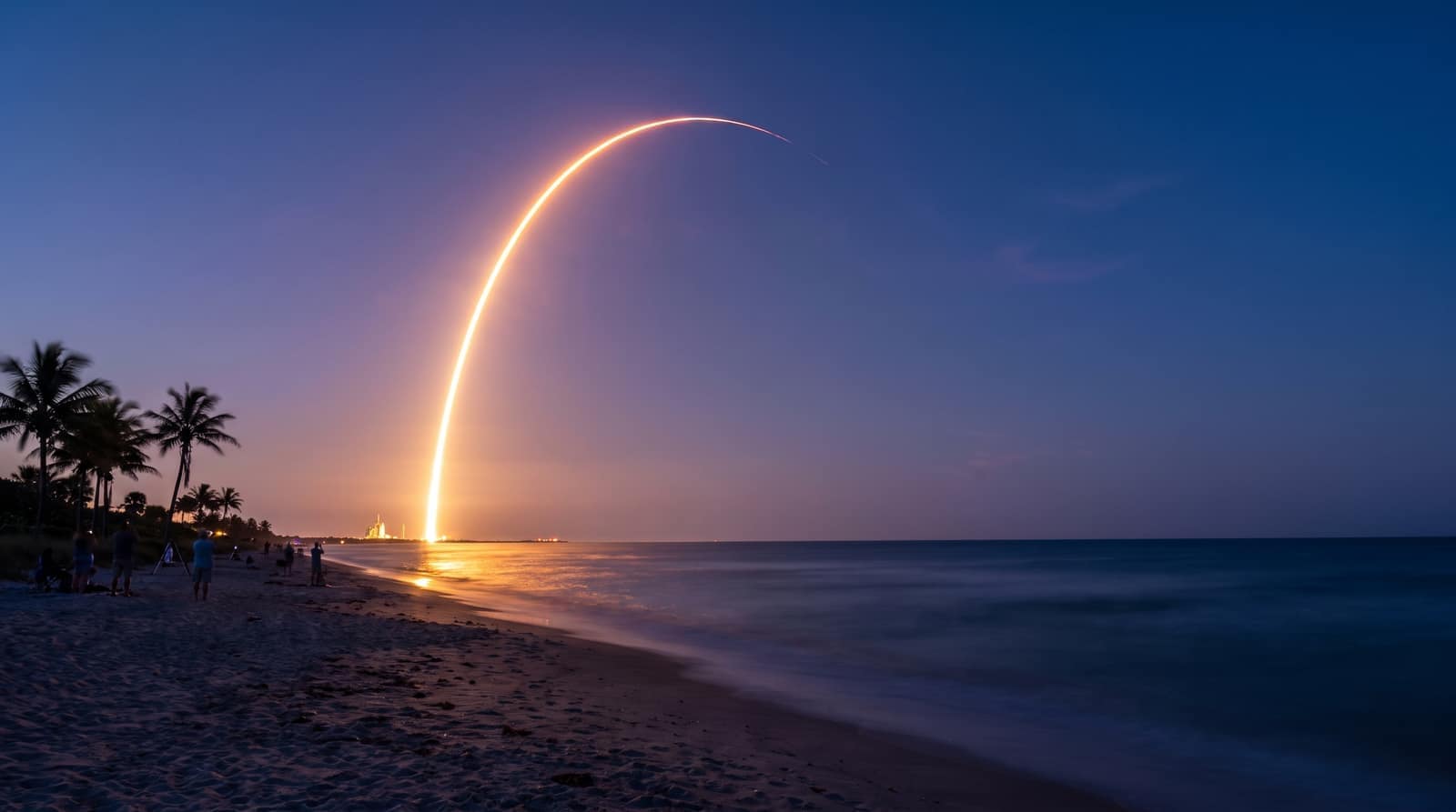A distant rocket launching into a dusk sky over the Atlantic, its glowing trail reflected on the water, seen from a Florida beach